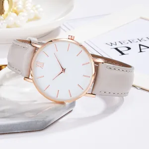 Κοντινό πλάνο μινιμαλιστικού ρολογιού rose gold με λευκό καντράν και δερμάτινο λουράκι