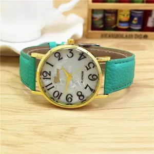 Women's gold watch with white marble dial and green leather strap on a wooden surface
