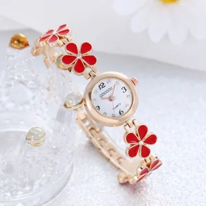 Dettaglio dell'orologio a bracciale a fiori oro rosa con petali rossi e cristalli