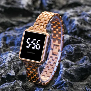 Montre numérique carrée tendance en or rose avec bracelet métallique sur fond rocheux