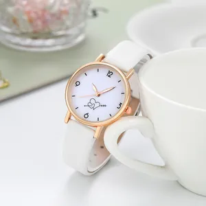Détails de la montre en or rose avec bracelet en cuir blanc et cadran cœur et flèche
