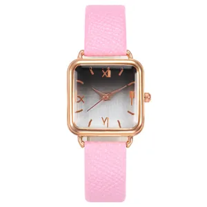 Détail d'une montre carrée en or rose avec cadran dégradé et bracelet en cuir rose