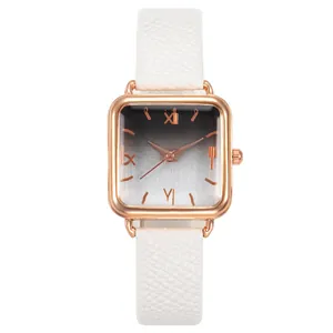 Détail du cadran carré en or rose avec chiffres romains et bracelet en cuir blanc élégant