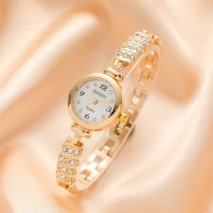 Elegant gold quartz watch for women with rhinestone-studded slim band on silk background