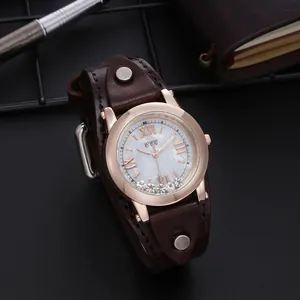 Détail de la montre or rose avec strass mobiles et bracelet en cuir vintage large