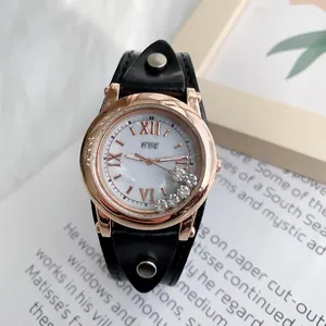 Détail d'une montre or rose avec cristaux mobiles et bracelet en cuir à rivets ronds