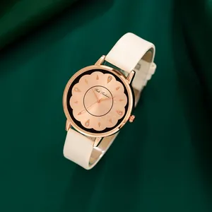 Détail d'une montre à cadran fleuri or rose avec bracelet en cuir blanc sur soie verte