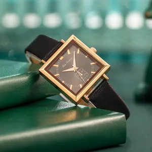 Elegant square gold watch with black leather strap on a decorative green box
