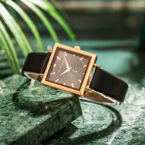Classic square gold quartz watch with leather strap displayed on green marble
