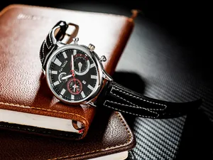 Detail of a business watch with leather strap on notebooks, showing date and red second hand