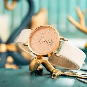 Elegante roségoldene Uhr mit weißem Lederarmband und Blumendetails auf Zifferblatt