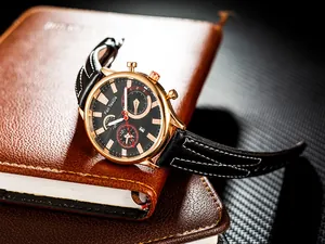 Detail of chronometer watch with black leather strap and date display on a leather notebook