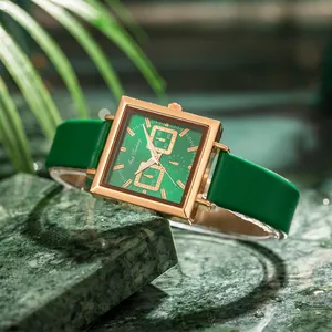 Women's rose gold square watch with forest green dial and leather strap on marble base