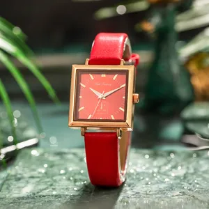 Detail of red square dial women's watch with golden case and leather strap on marble