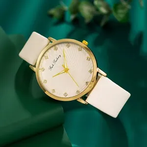 Detailansicht eines goldenen Zifferblatts mit Kristallmarkierungen und weißem Lederband