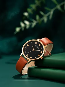 Primer plano de reloj para mujer con esfera estrellada sobre libros verdes