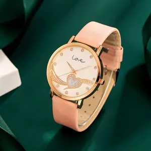 Détail de montre or rose avec cœur scintillant et texte Love sur un grand cadran blanc