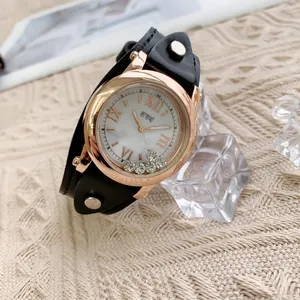 Détail d'une montre en or rose avec cristaux flottants et bracelet en cuir noir clouté