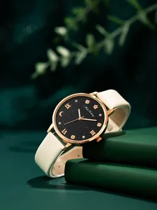 Detalle de una esfera de reloj negra estrellada con detalles en oro rosa sobre un libro