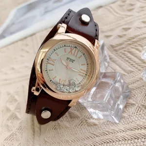 Détail du cadran rose doré avec zircons mobiles et bracelet en cuir marron à rivets