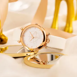 Orologio minimalista in oro rosa con cinturino in pelle bianca su sfondo dorato riflettente