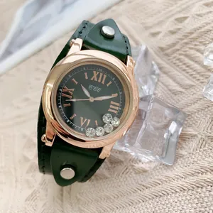 Détail de montre or rose avec strass mobiles et bracelet en cuir vert à rivets