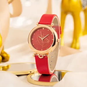Dettaglio di un orologio minimalista in pelle rossa con cassa dorata e quadrante a spirale