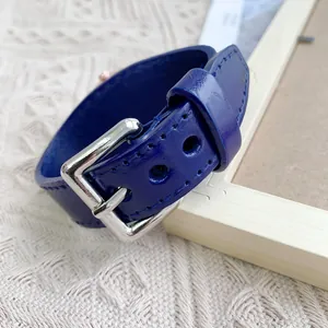 Détail d'un bracelet de montre en cuir bleu foncé avec boucle argentée et couture