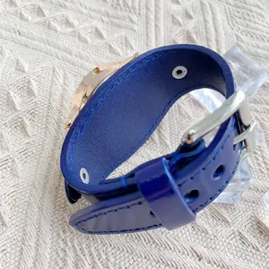 Détail d'un bracelet en cuir bleu avec boucle en or rose et trous de réglage sur une montre