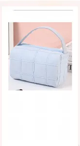 Detail of light blue quilted cosmetic bag with soft checkered texture and sturdy handle