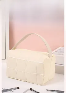 Close-up of cream quilted travel makeup bag with plush trim and soft carry handle