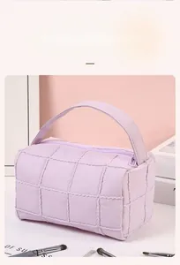 Close-up of lilac quilted makeup bag with square texture and top handle for travel storage