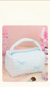 Detailed view of light blue checkered makeup bag with satin bows and lace trim