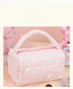 Detail of pink plaid makeup bag featuring lace edges and decorative silk bows