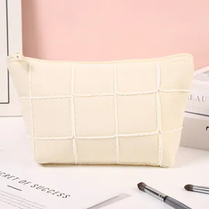 Minimalist cream quilted cosmetic bag with grid pattern and zipper for travel storage