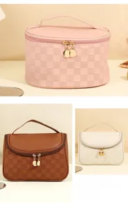 Detail of checkered PU leather makeup bags with golden circular metal zippers and handles