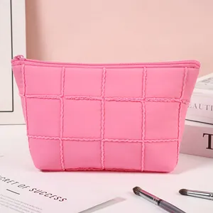 Pink quilted travel makeup bag with grid pattern and top zipper for cosmetic storage