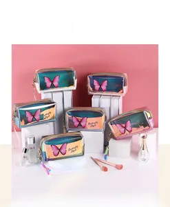 Iridescent laser butterfly makeup bags displayed on geometric stands with wristlet straps