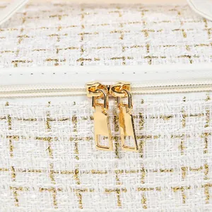 Elegant white and gold tweed makeup bag with dual gold zippers and premium finish