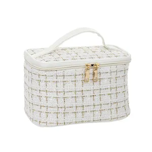 Elegant white tweed vanity case with gold zippers and top handle for makeup storage