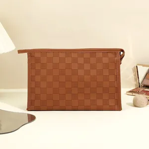 Brown checkerboard PU leather makeup bag with zipper closure on a vanity desk