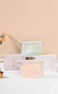 Detail showing four pastel mesh toiletry bags with floral embroidery and white zippers