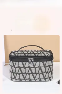 Detail of fabric toiletry bag with geometric V-pattern, leather handle and metal zipper