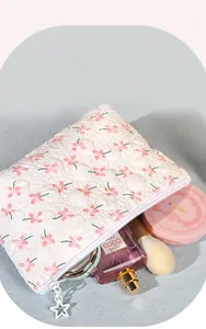 Neceser bordado floral con cremallera de estrella mostrando cosméticos en el interior