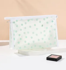 Close-up of semi-transparent mesh makeup bag with green floral pattern and zipper