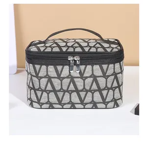 Detail view of large grey cosmetic bag with geometric V-pattern and metal dual zippers