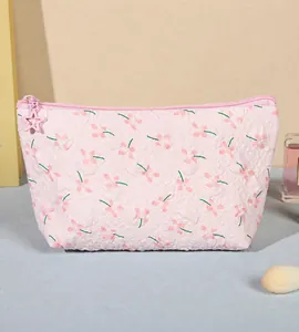 Detalle de neceser floral rosa con tela en relieve y un tirador de cremallera de estrella