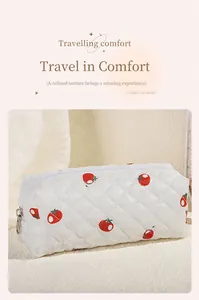 Detailed macro shot of white quilted strawberry makeup bag with silver metal zipper pull