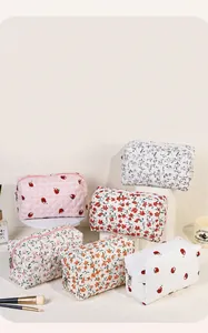Macro detail of quilted floral cosmetic bags with strawberries and zipper closures