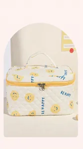 Dettaglio della borsa da toilette trapuntata bianca con smiley giallo e ricamo a lettere